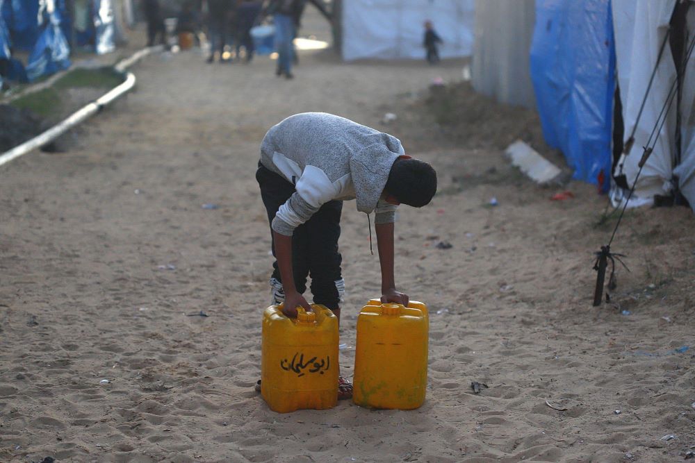 Children use the underground water line to obtain drinking water in Khan Yunis, southern Gaza Strip